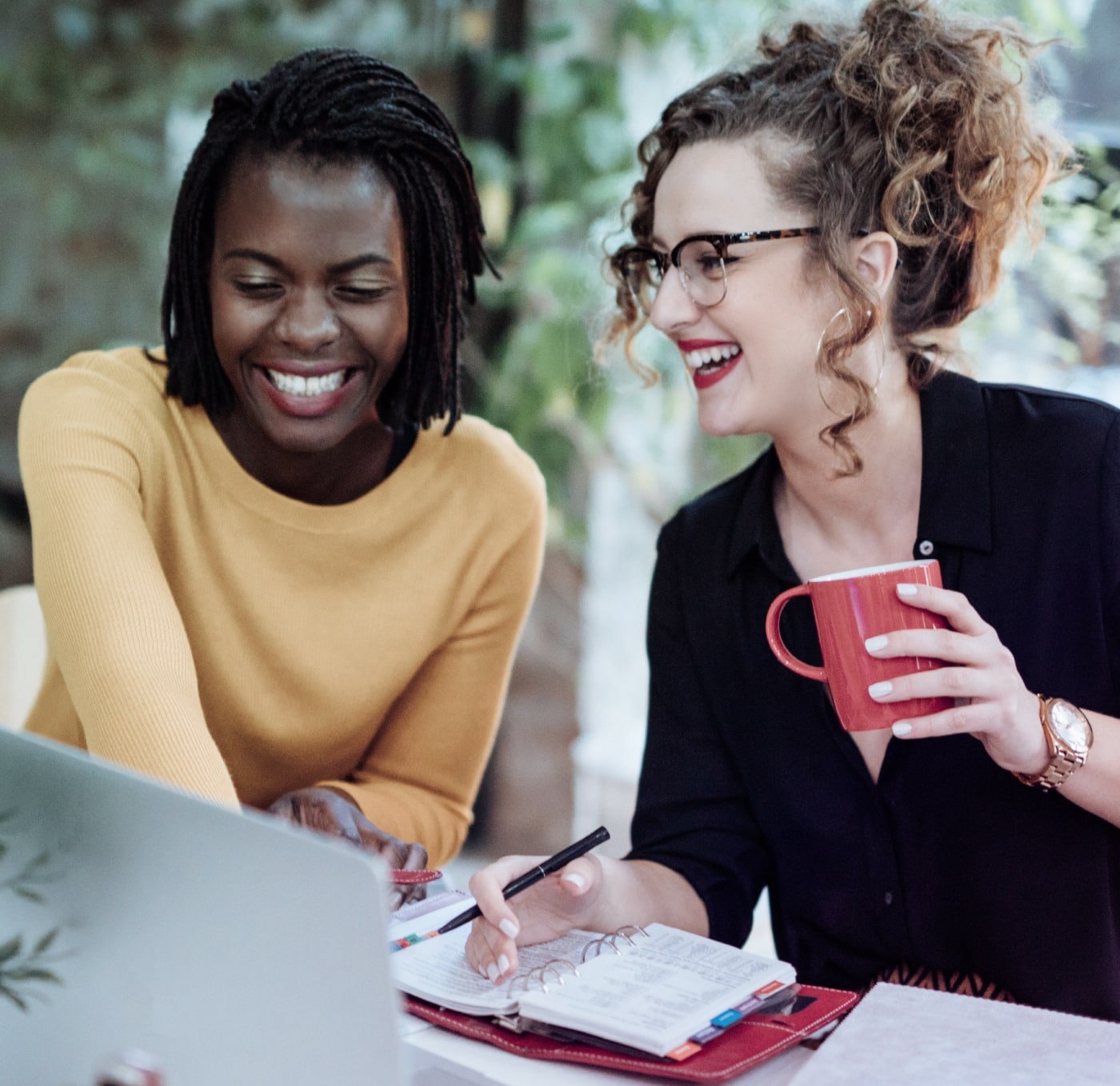 Two women sitting at a table looking at a laptop